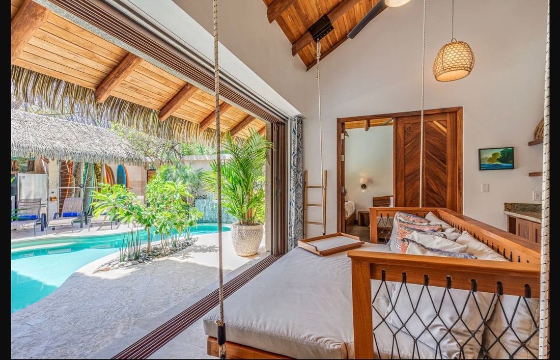 A bedroom with its doors folded back, opening straight onto the pool deck