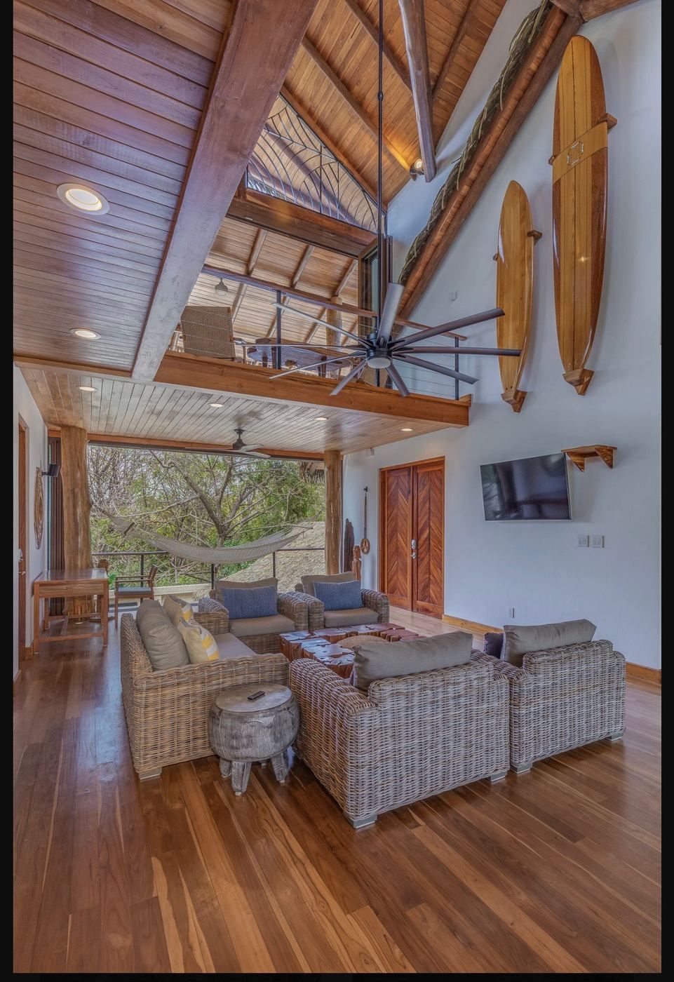 The great room under its vaulted timber ceiling, surfboards along the wall